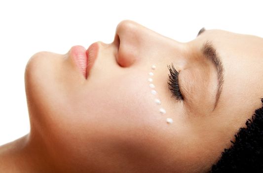 Close-up of beautiful woman face receiving an eye cream treatment