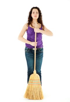 Young woman standing holding a broom, staring at camera, isolated