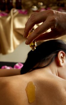 essential oil poured on a female back in spa centre
