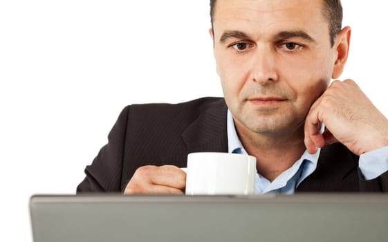 Portrait of businessman behind laptop drinking coffee, isolated
