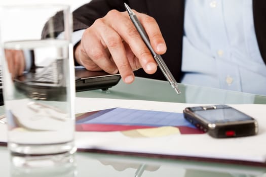 Close-up of businessman hand holding pen while working over documents