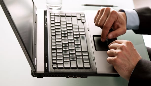 Close-up of male hands using laptop on desk