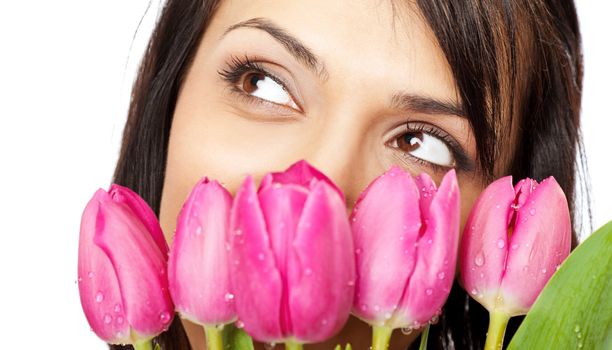 beautiful young female face behind bouquet of pink tulips