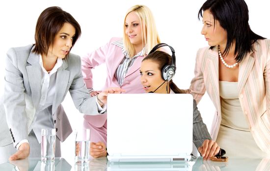 Successful team of four businesswomen talking behind desk with laptop, one with headset