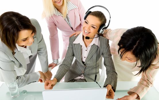 Team of four businesswomen smiling behind laptop, one with headset