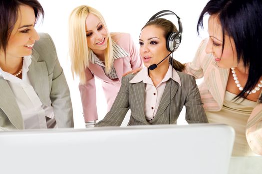 Four beautiful successful businesswomen talking behind laptop, one of them with headset