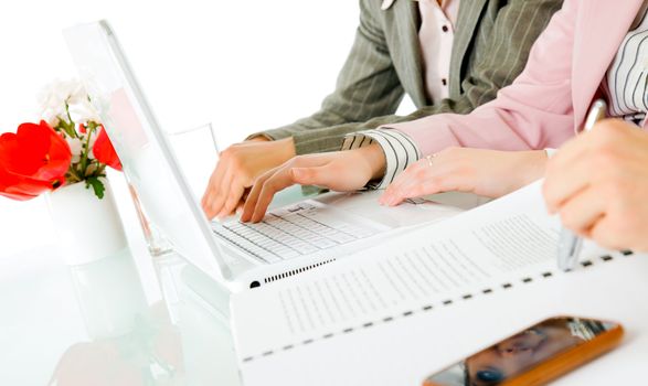 Close-up of female hands behind desk, in front of laptop and documents