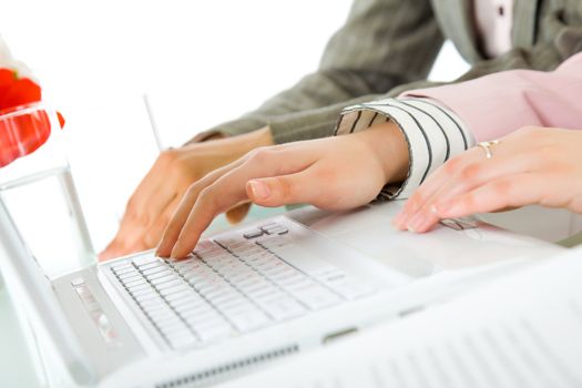 Close-up of female hands using ciralised laptop on desk