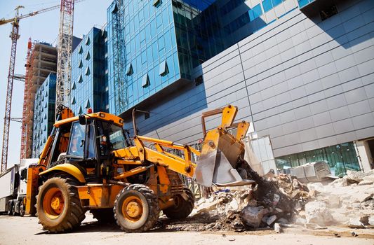 excavator is digging rubble in front of a modern building in construction