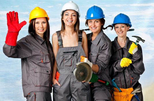 Four happy female construction workers posing with instruments on beach, studio