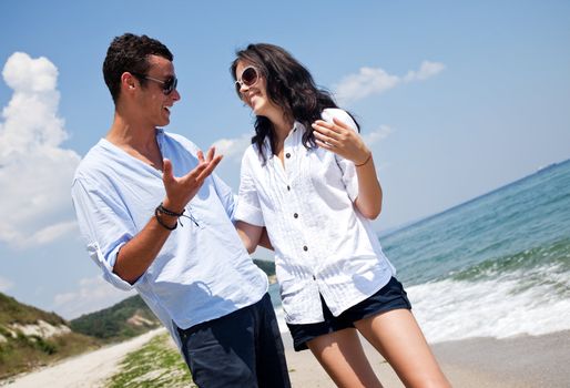 Young happy couple hugging and talking along a solitary beach