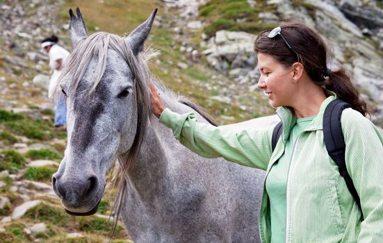 a young woman is petting a horse in the mountains