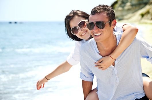 piggyback ride to beautiful female on solitary beach, happy couple