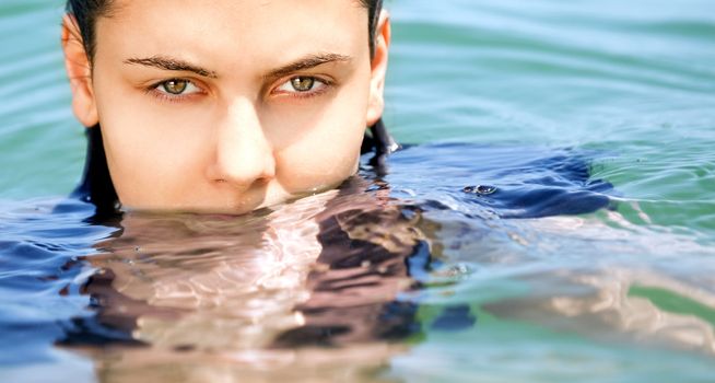 Close-up of young females face in the water, looking at camera