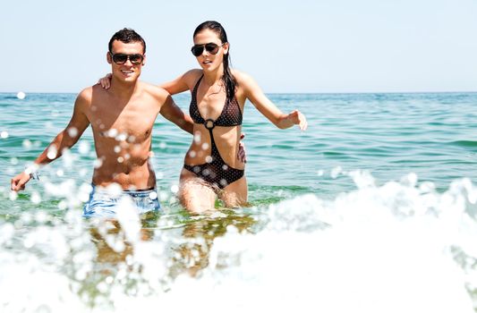 Young couple with sunglasses hugging and going out of sea