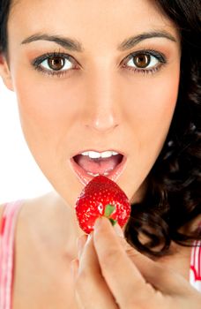 Close-up of young beautiful female eating strawberry, looking at camera