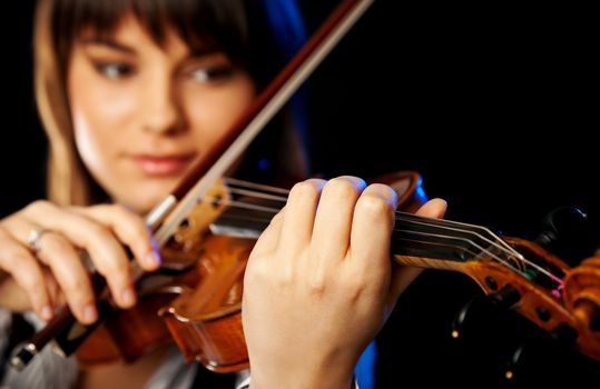 beautiful girl playing violin, selective focus on the front hand