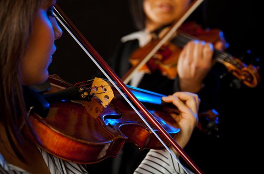 two violinists playing violins on a black background