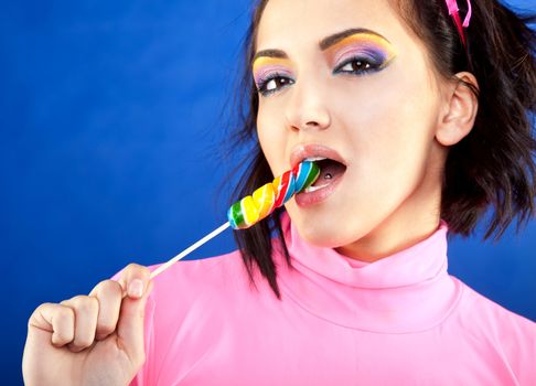 Beautiful female licking a lollipop on blue background