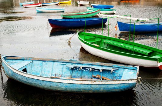 old boats in calm water. blue one at the front with broken seat