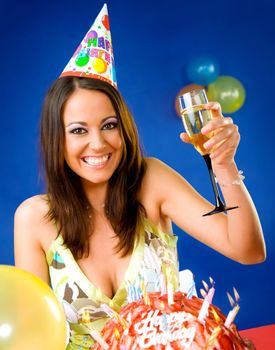Happy female celebrating with glass of champagne and party hat over birthday cake