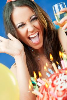Happy female smiling behind birthday cake with burning candels