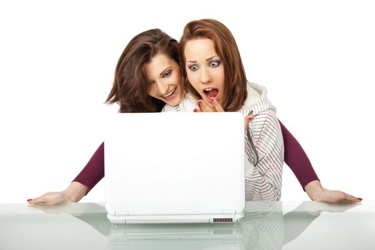 Two beautiful girls sitting behind a laptop very surprised