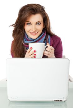 Young beautiful female sitting behind laptop, holding a cup smiling