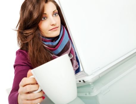 beautiful young female sitting behind laptop with a cup