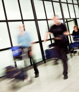 Blurred figures of people with luggage arriving at airport