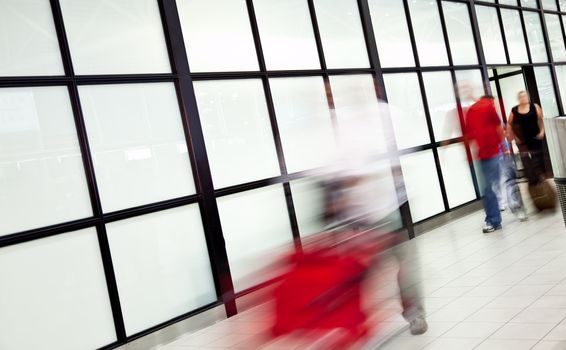 Blurred figures of people at airport, arriving with luggage