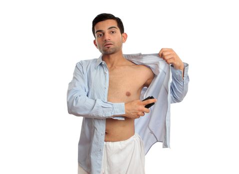 A man spraying a deodorant body spray under arms while getting dressed.