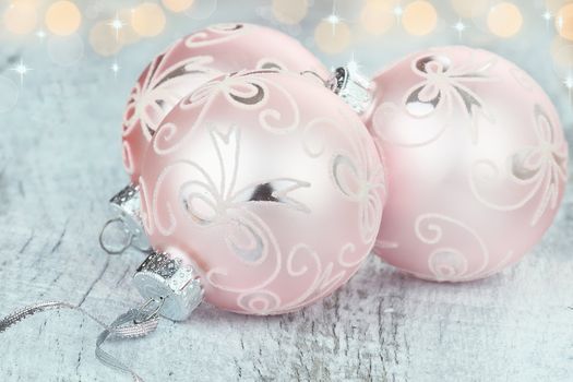 Pink Christmas ornaments lying on a rustic table. Shallow depth of field.