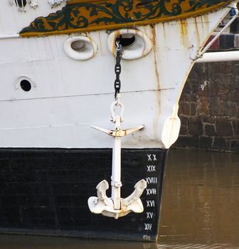 A white iron anchor on a chain from a ship