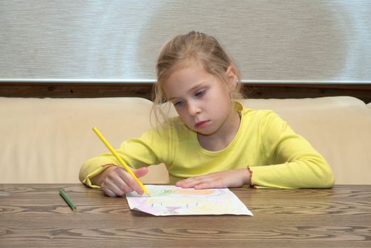 Portrait of the thoughtful lovely girl drawing color pencils.