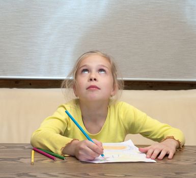 Blonde girl with colored pencil thoughtfully looking up.