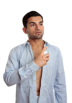A man in the process of getting ready and dressed, sprays some cologne on skin.