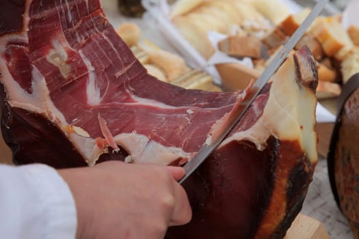 A hand cutting prosciutto
