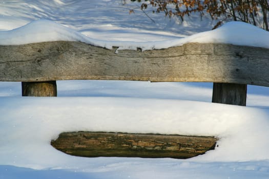 Wooden bench covered with snow