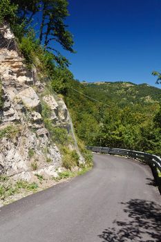 mountain road with curve under a bright blue sky