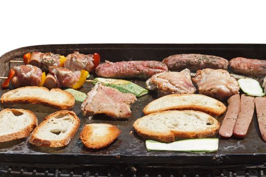 barbecue with meat, sausage, bread and vegetables isolated on white