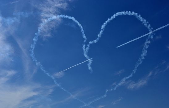 Tree planes drawing a heart in the blue sky
