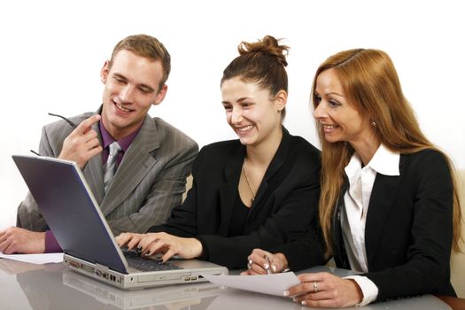 Friendly team working in the office. Two women and a man sitting in front of a computer and smiling. Horizontal format and text space