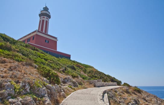 Concept of direction with this road and lighthouse. Copy space on blue background.