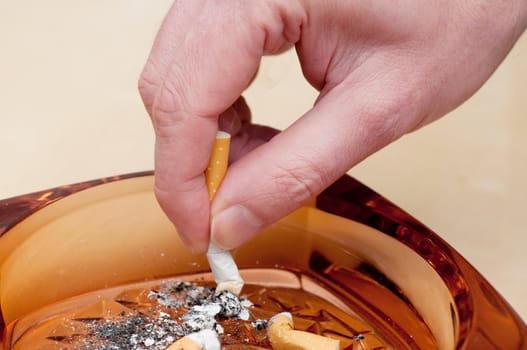 Detail of Males hand Stubbing Out Cigarette in Ashtray
