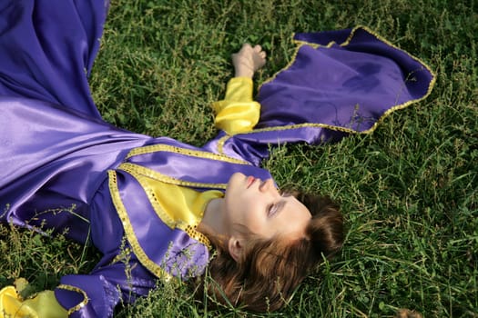 Young womai in a fancy dress laying on grass