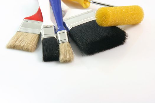 detail from four paint brushes and paint roll on white background hardware tools with copy space