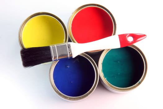 white small paint brush on four open paint cans on white background