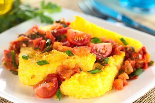 Polenta slices with Hogao, also called Criollo Sauce, which is a Colombian sauce made of tomato, onion and cilantro (Selective Focus, Focus one third into the dish)