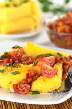 Polenta slices with Hogao, also called Criollo Sauce, which is a Colombian sauce made of tomato, onion and cilantro (Selective Focus, Focus on the front of the two tomato quarters)